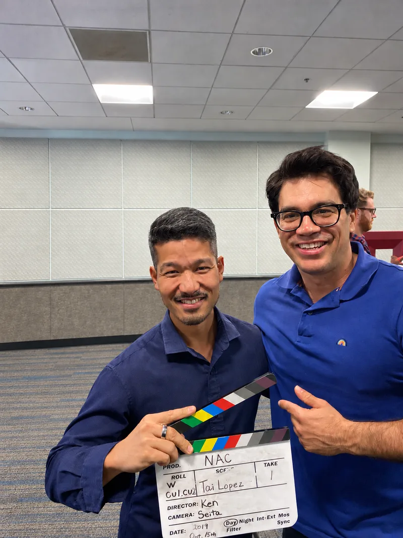Ken Okazaki holding a clapperboard with Tai Lopez